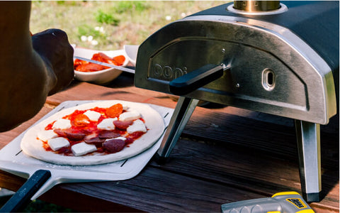 Pizza on a peel in front of an oven